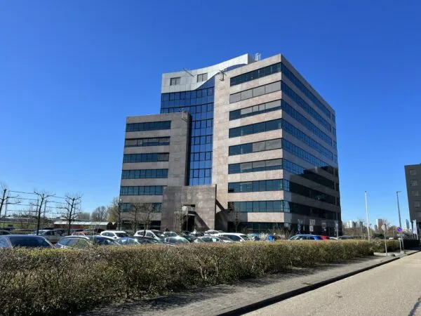 Zakelijk kantoorgebouw aan het Rivium Quadrant met parkeerplaats op de voorgrond en een heldere blauwe lucht.
